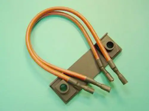 Zündkabel mit zwei orangefarbenen Leitungen, befestigt an einer grauen Platte. Produkt von Remeha, verwendet in bestimmten Heizungs- oder Motorsystemen.